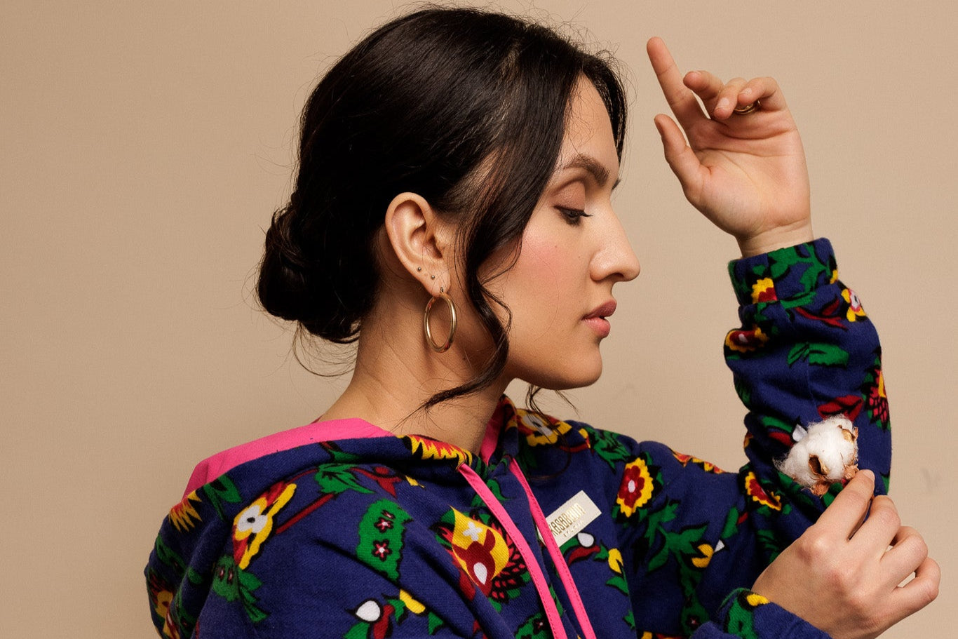 A young woman wearing the Kasabada Studio sunflower Blues sweatsuit while holding cotton flower in her hand from the side
